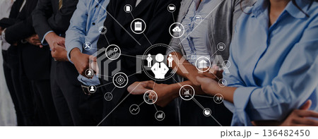 Professional group standing in a line with technology icons representing networking, digital communication, and team collaboration in a modern workspace setting Trope 136482450