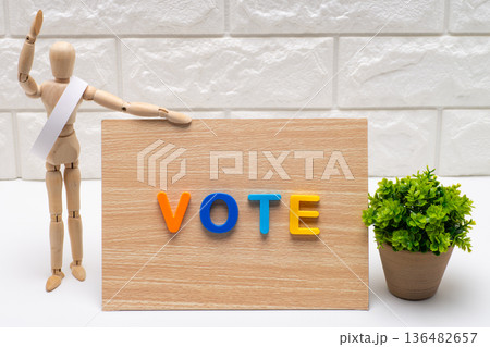 タスキを掛けた選挙の候補者と投票を促す看板 タスキを掛けた選挙の候補者と投票を促す看板 136482657