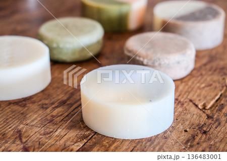 Natural handmade artisan round soap bars displayed on a rustic wooden table. Organic skincare products with minimalist design. 136483001