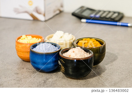 Colorful natural cosmetic ingredients in small ceramic bowls on a table. 136483002