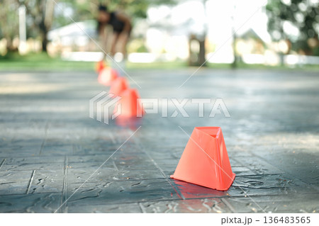 Woman placing training cones on pavement to prepare agility and speed workout, focus on training cones 136483565