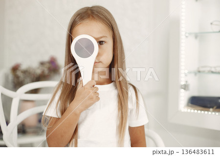 Child eye test and eye exam. Little girl having eye check-up, with phoropter. Eye test for children. Child eye test and eye exam. Little girl having eye check-up, with phoropter. Eye test for children. 136483611