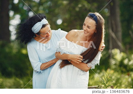 Women in a summer forest. Lady in a blue dress. Family posing and embracing. 136483676