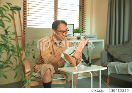 Middle aged man cleaning a prosthetic leg at home Middle aged man cleaning a prosthetic leg at home 136483839