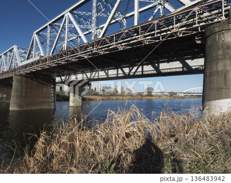 多摩川橋梁を見上げる迫力の構図と冬の河川敷、青空に映えるトラス鉄橋 136483942