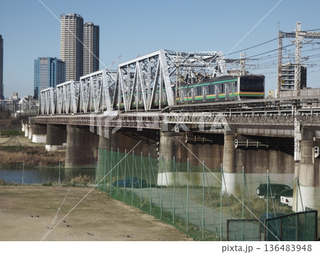 多摩川橋梁を渡るJR東日本のE233系電車と川崎のタワーマンション群 136483948