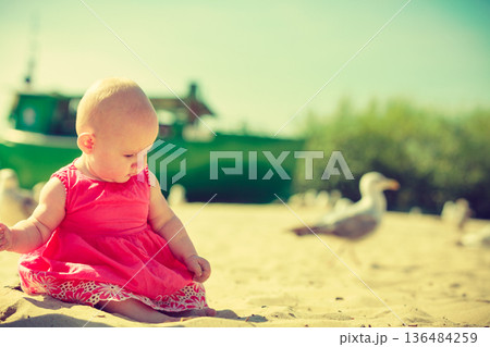 Little baby sitting and playing on beach Little baby sitting and playing on beach 136484259