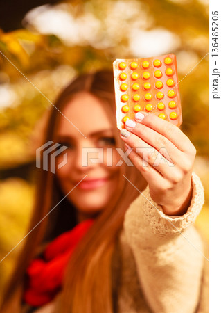 Woman in autumn park holding vitamins medicines Woman in autumn park holding vitamins medicines 136485206