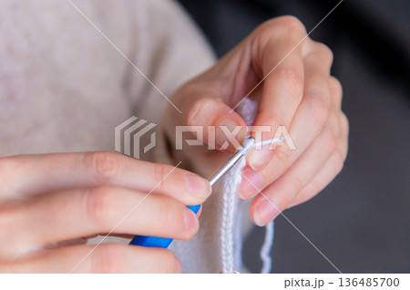 Young happy woman crocheting at home relaxing and meditating Young happy woman crocheting at home relaxing and meditating 136485700