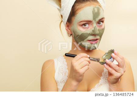 Woman applying with brush clay mud mask to her face Woman applying with brush clay mud mask to her face 136485724