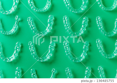 Clear aligners and braces on a colored background. Many clear hedgehog braces on a colored background. Dental background. Technological dentistry. Clear aligners and braces on a colored background. Many clear hedgehog braces on a colored background. Dental background. Technological dentistry. 136485755