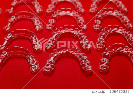 Clear aligners and braces on a colored background. Many clear hedgehog braces on a colored background. Dental background. Technological dentistry. Clear aligners and braces on a colored background. Many clear hedgehog braces on a colored background. Dental background. Technological dentistry. 136485825