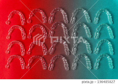 Clear aligners and braces on a colored background. Many clear hedgehog braces on a colored background. Dental background. Technological dentistry. Clear aligners and braces on a colored background. Many clear hedgehog braces on a colored background. Dental background. Technological dentistry. 136485827
