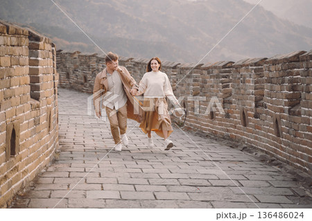 young couple running and twirling at the Great Wall of China. Newly married couple on their honeymoon to the Great Wall of China near Beijing China. young couple running and twirling at the Great Wall of China. Newly married couple on their honeymoon to the Great Wall of China near Beijing China. 136486024