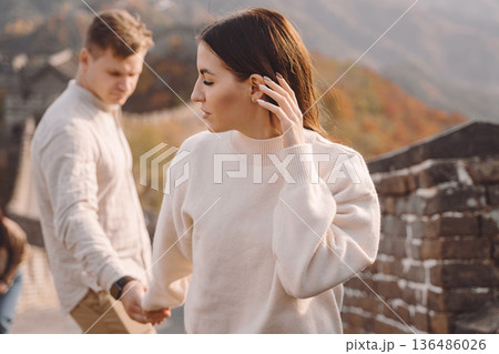 beautiful young couple holding hands and showing affection at the Great Wall of China. Newly married couple on their honemoon to Great Wall near Beijing China. Stylish couple exploring one of the beautiful young couple holding hands and showing affection at the Great Wall of China. Newly married couple on their honemoon to Great Wall near Beijing China. Stylish couple exploring one of the 136486026