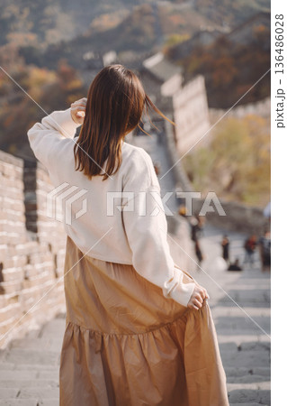 stylish girl visiting the Great Wall of China near Beijing during autumn season. Brunette girl dancing at one of the 7 wonders of the world. stylish girl visiting the Great Wall of China near Beijing during autumn season. Brunette girl dancing at one of the 7 wonders of the world. 136486028