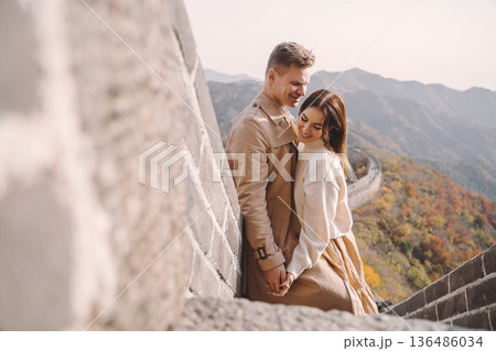 beautiful young couple showing affection on the Great Wall of China. Newly married couple on their honemoon to Great Wall near Beijing China. Stylish couple exploring one of the wonders of the world beautiful young couple showing affection on the Great Wall of China. Newly married couple on their honemoon to Great Wall near Beijing China. Stylish couple exploring one of the wonders of the world 136486034