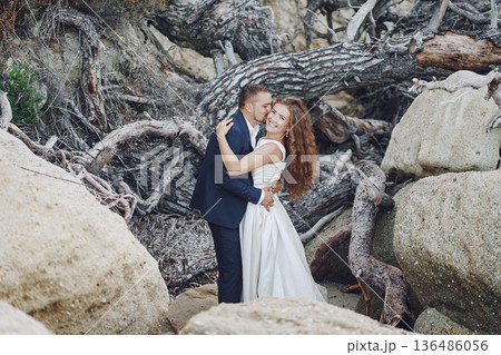 beautiful young long-haired bride in white dress with her young husband near gray branches beautiful young long-haired bride in white dress with her young husband near gray branches 136486056