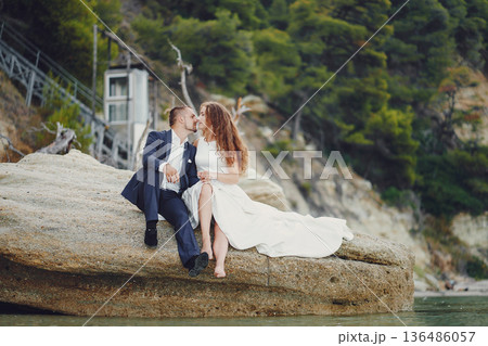 beautiful young long-haired bride in white dress with her young husband near river beautiful young long-haired bride in white dress with her young husband near river 136486057