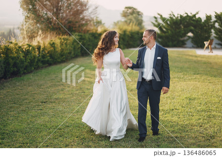 beautiful long-haired bride in white dress with her young man walking in the nature beautiful long-haired bride in white dress with her young man walking in the nature 136486065