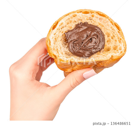 Croissant cut in half with chocolate cream filling in female hand isolated on white Croissant cut in half with chocolate cream filling in female hand isolated on white 136486651