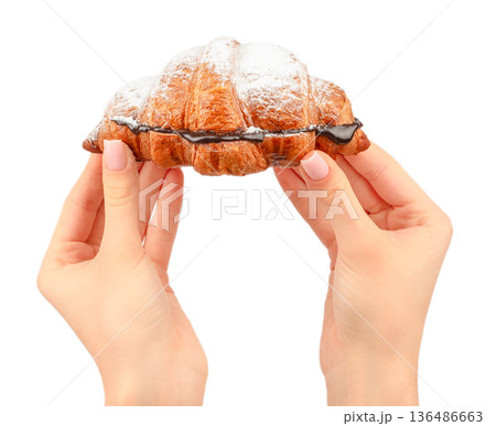 Chocolate filled croissant with powdered sugar held in female hands isolated on white Chocolate filled croissant with powdered sugar held in female hands isolated on white 136486663