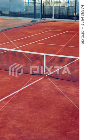 Tennis court with net in middle on a sunny day at a sports facility Tennis court with net in middle on a sunny day at a sports facility 136486974
