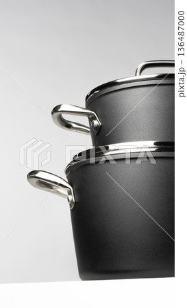 Nice black cooking pots stacked on a white shelf in a modern kitchen setting Nice black cooking pots stacked on a white shelf in a modern kitchen setting 136487000