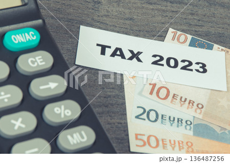 Calculator, inscription tax 2023 and euro banknotes. Calculating and paying tax 136487256