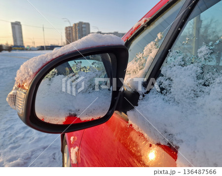 Snow clings to the side mirror of the red car Snow clings to the side mirror of the red car 136487566