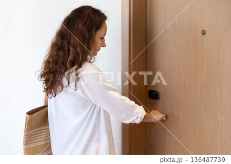 Adult caucasian woman opening hotel room door with keycard, travel lifestyle concept 136487739