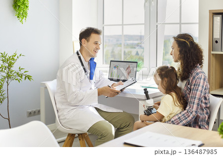 Pediatrician reviewing notes with mother and daughter at family appointment 136487985