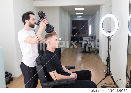 Barber drying client hair in modern salon 136489672