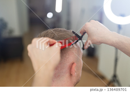 Barber cutting man's hair creating a fresh style Barber cutting man's hair creating a fresh style 136489701