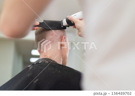 Barber cutting man's hair with electric clipper Barber cutting man's hair with electric clipper 136489702