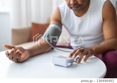 Mature black man measuring blood pressure at home using digital monitor 136490481