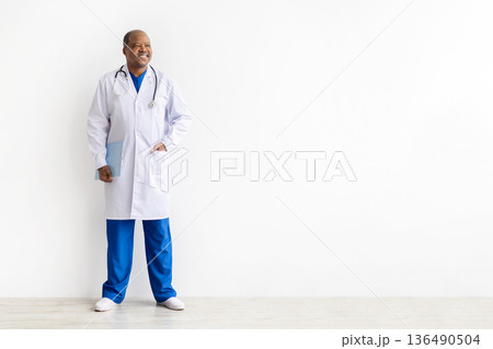 Mature black male doctor wearing white coat and holding clipboard 136490504