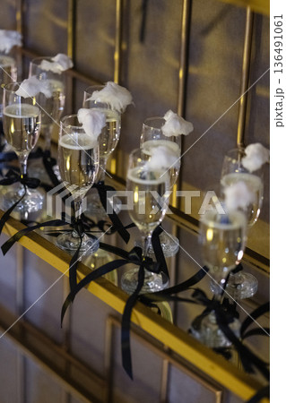 Champagne flutes topped with cotton candy on golden shelf with black ribbons Champagne flutes topped with cotton candy on golden shelf with black ribbons 136491061