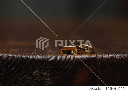Two gold wedding rings on dark wooden surface with dark background Two gold wedding rings on dark wooden surface with dark background 136491065