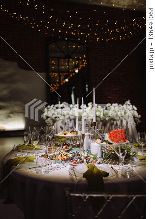 Wedding banquet tables with floral decor in loft hall with brick walls and garland lights Wedding banquet tables with floral decor in loft hall with brick walls and garland lights 136491068