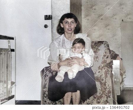 A vintage portrait of a little girl and her mother. The mother holds the child in her arms. Retro photograph from 1995. 136491702