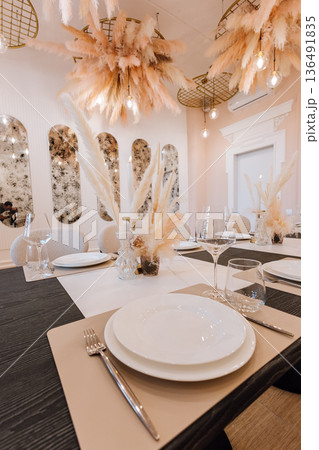 Elegant private dining table with pampas centerpieces, candles and modern tableware Elegant private dining table with pampas centerpieces, candles and modern tableware 136491835