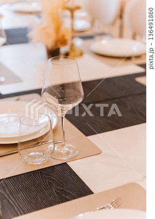 Close up of elegant glassware on modern dining table with soft bokeh and neutral tones Close up of elegant glassware on modern dining table with soft bokeh and neutral tones 136491860