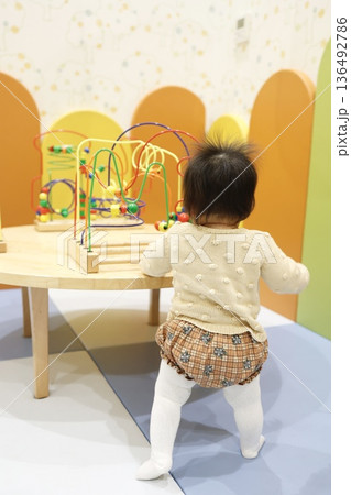 つかまり立ちで遊ぶ赤ちゃんの後ろ姿。 つかまり立ちで遊ぶ赤ちゃんの後ろ姿。 136492786
