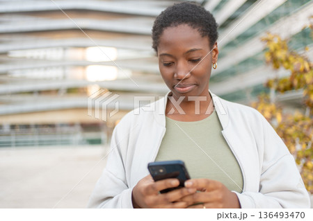 Young businesswoman using smartphone in front of 136493470