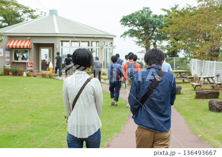 曇り空が広がる公園を歩いている大学生の団体客 136493667