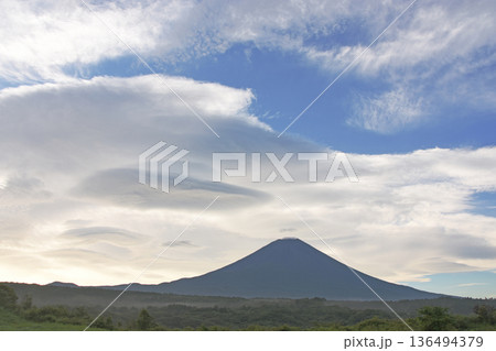 夏の清涼とした高原の中央にすっと立つ全身が群青色の秀麗な富士山と空に浮かぶいくつもの吊るし雲 136494379