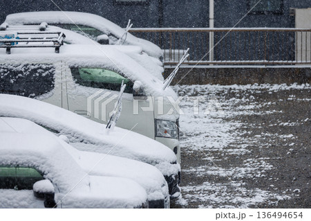 雪の日に凍結防止でワイパーを立てて駐車された車列 136494654
