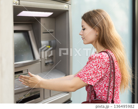 Young woman carefully entering pin code at atm Young woman carefully entering pin code at atm 136495982