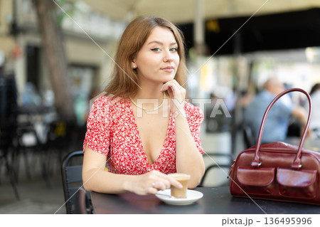 Young woman drinking coffee in glass mug Young woman drinking coffee in glass mug 136495996